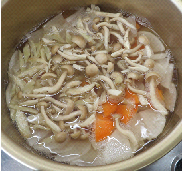 大根とにんじんとごぼうとしめじをだし汁で煮ている写真