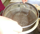 沸騰した鍋にザルを入れている写真